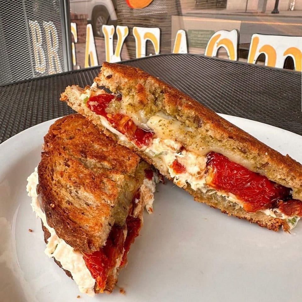 A grilled sandwich from Mr. J's Deli, filled with roasted red peppers and creamy white cheese.