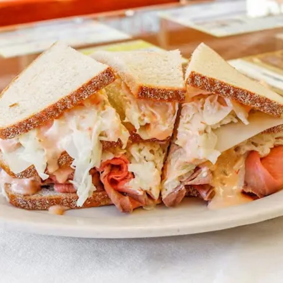 A Mr. J's Deli sandwich with roast beef, coleslaw, cheese, and Russian dressing on rye bread.